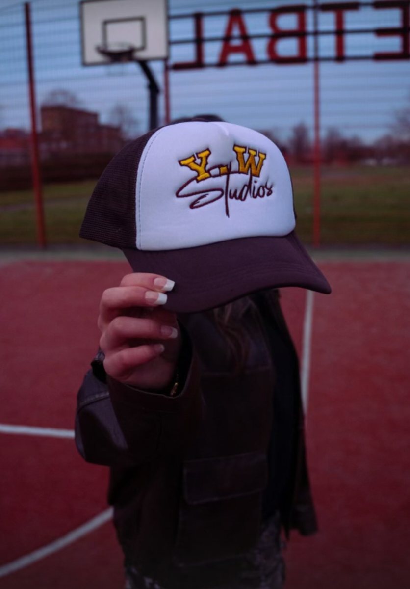 White and brown trucker cap with the gold Y.W Studios embroidery